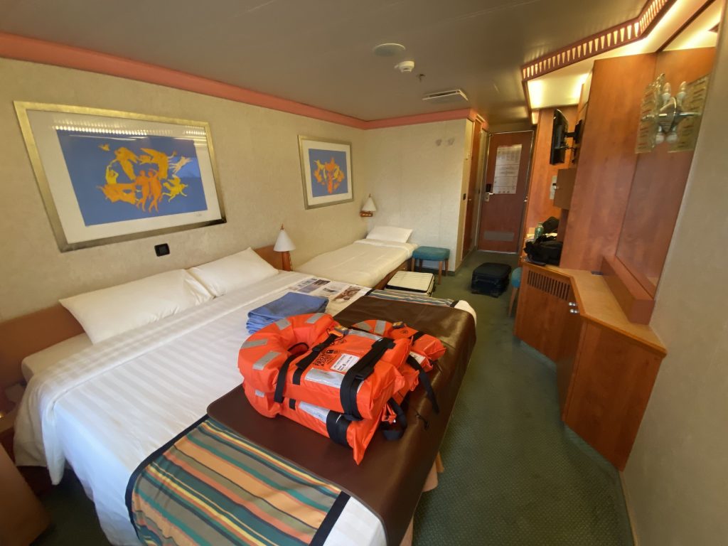 歌詩達陽台房：從陽台方向看整個房間的全景，右側有電視、冰箱、梳妝台、保險櫃等